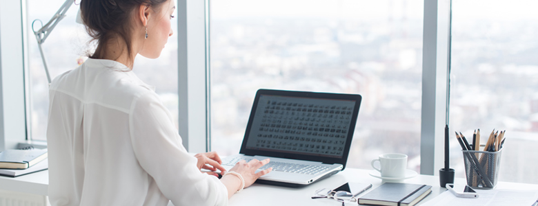 Woman working on a laptop in front of a large window